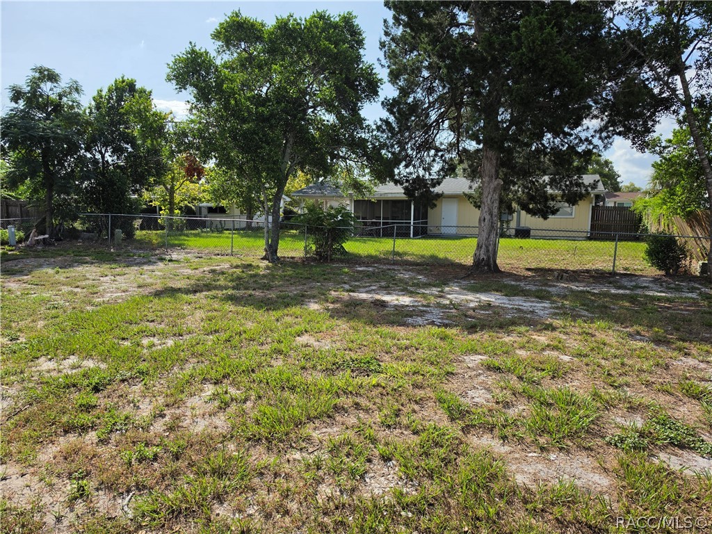 Home behind a fenced, patchy yard with mature trees.
