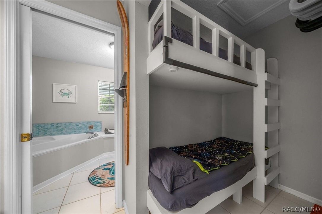 Bedroom with a white built-in bunk bed beside an open doorway to a tiled bathroom.