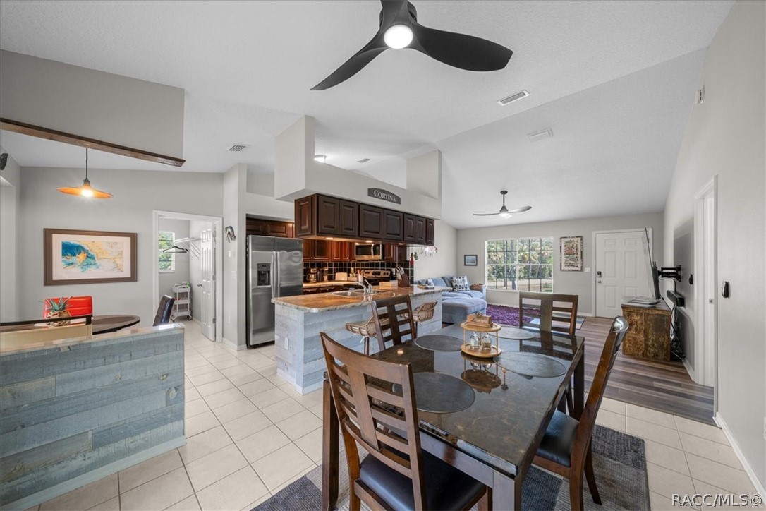 Open kitchen and dining area with a large island, dark wood cabinets, and stainless steel appliances.