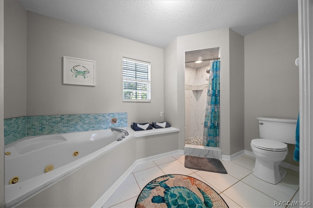 Bathroom with a jetted soaking tub and a marble-look walk-in shower with a blue curtain.