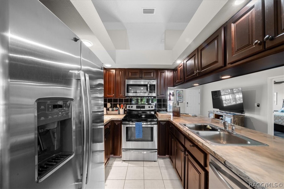 Kitchen with dark wood cabinetry, stainless steel appliances, and a double-basin sink.