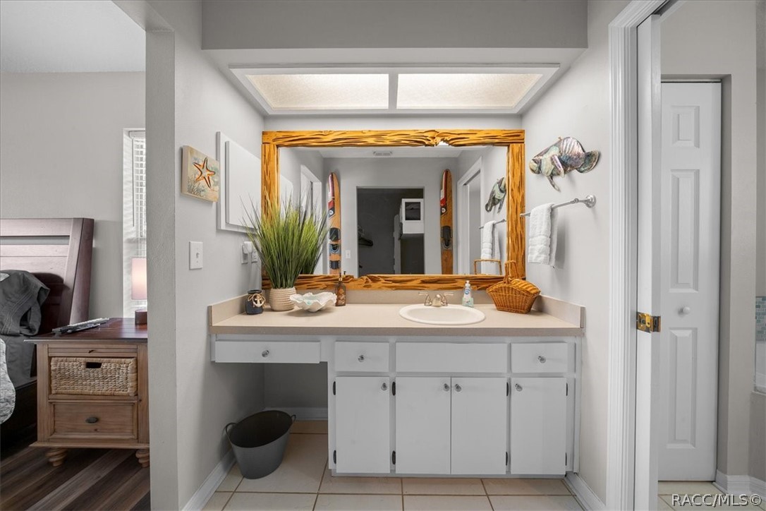 Bathroom vanity with a white sink cabinet, beige counter, and large wooden-framed mirror.