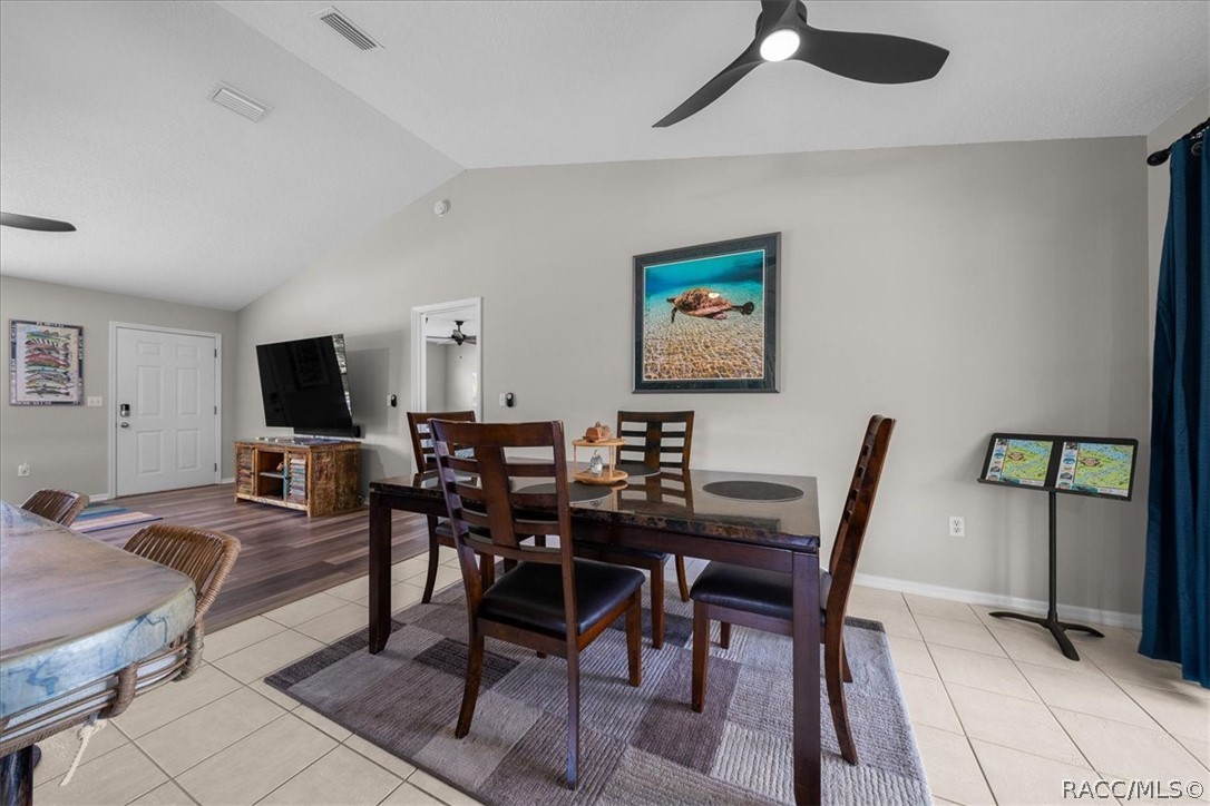 Dining area with a dark wood table, tiled floor, ceiling fan, and framed sea turtle artwork.