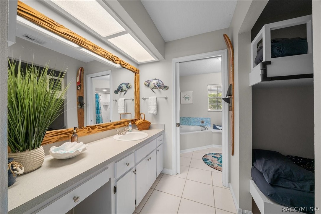 Bathroom with a long white vanity, wood-framed mirror, tiled floor, and built-in bunk beds.