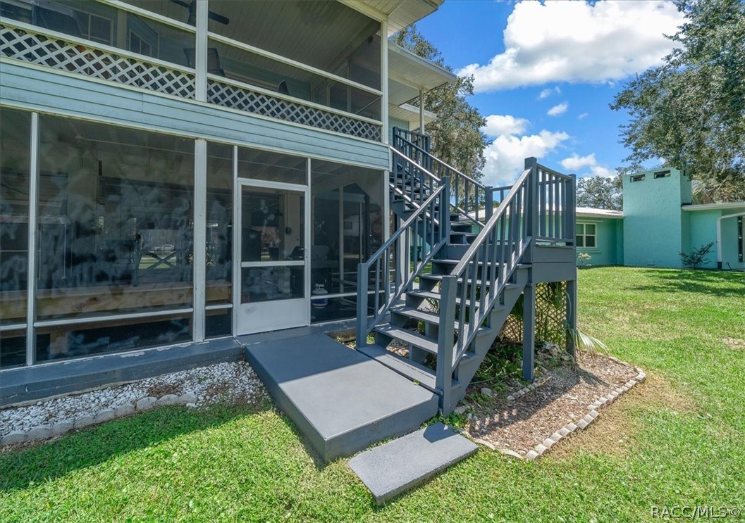 Light aqua home with a screened porch and raised wooden stairs leading to the yard.