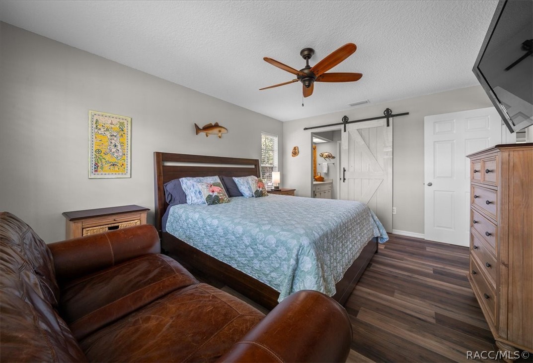 Furnished bedroom with a pale blue quilt, brown leather sofa, and white sliding barn door.
