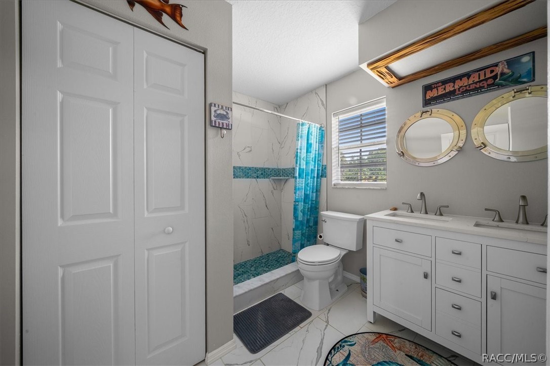 Bathroom with a double vanity, porthole-style mirrors, and a turquoise-accented tiled shower.