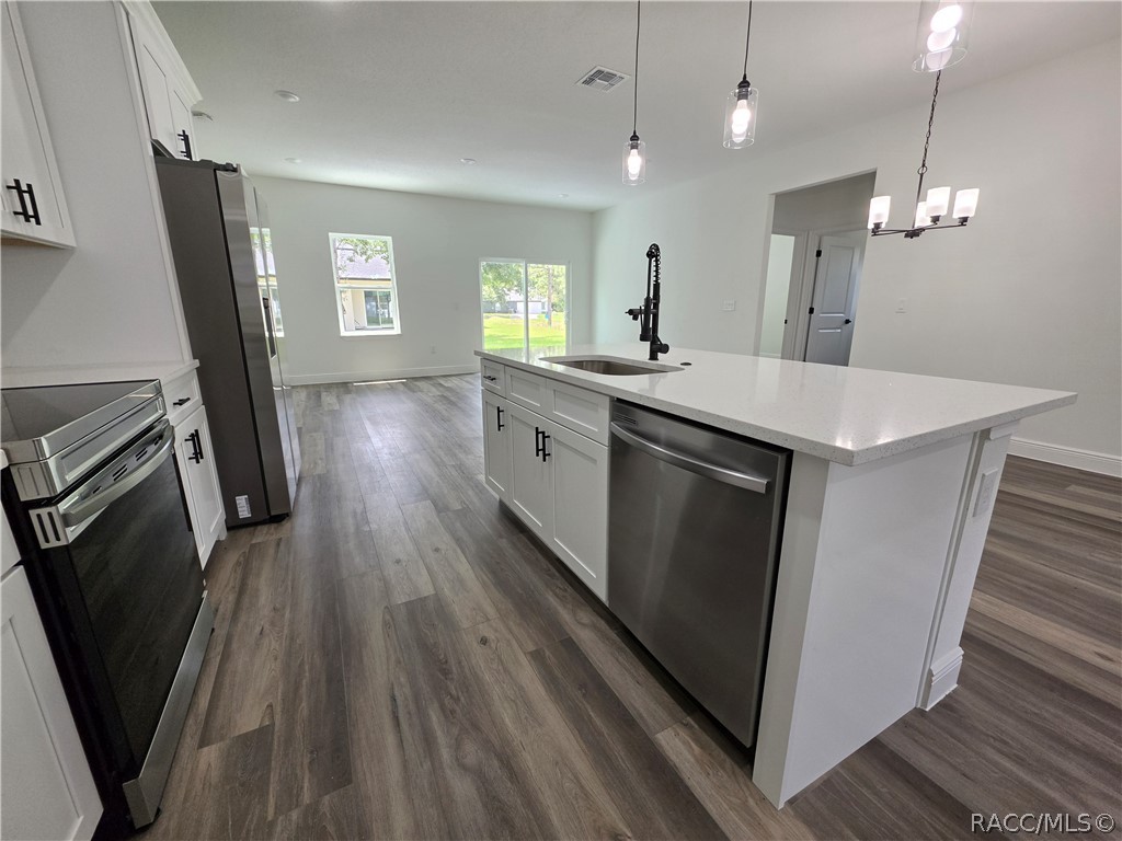 Bright kitchen with large white island, stainless appliances, and sliding doors opening to the yard.
