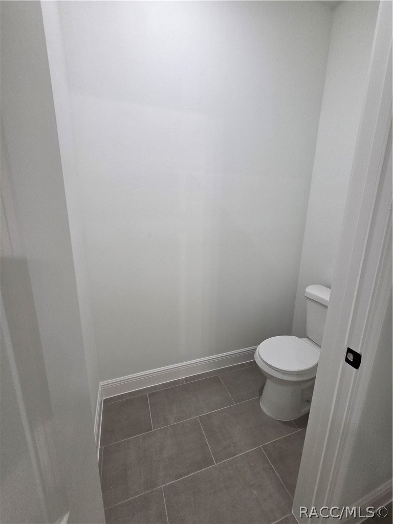 Unfurnished bathroom with a white toilet and gray tile floor.