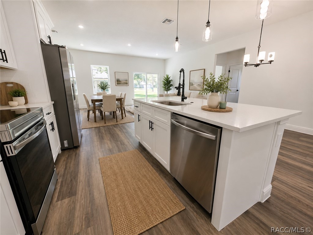 Staged kitchen with a large white island, stainless steel appliances, and an adjoining dining area.
