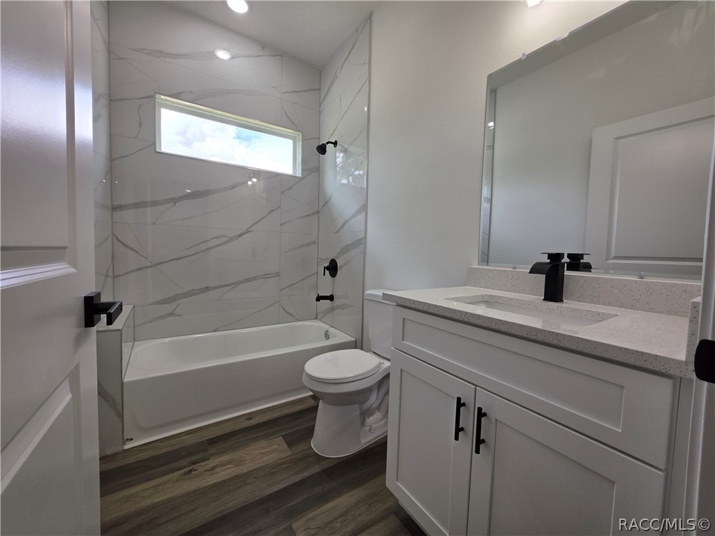 Bathroom with a veined tile tub surround, narrow window, white vanity, and dark fixtures.