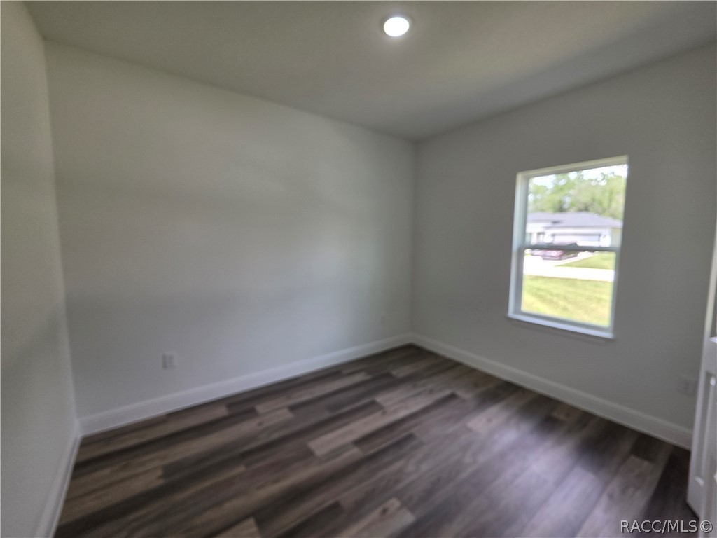 Vacant room with dark wood-look flooring, gray walls, and a window.