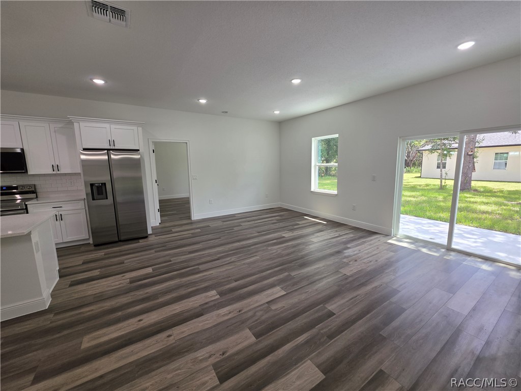 Open kitchen and living area with white cabinetry, stainless appliances, and sliding glass doors to the yard.