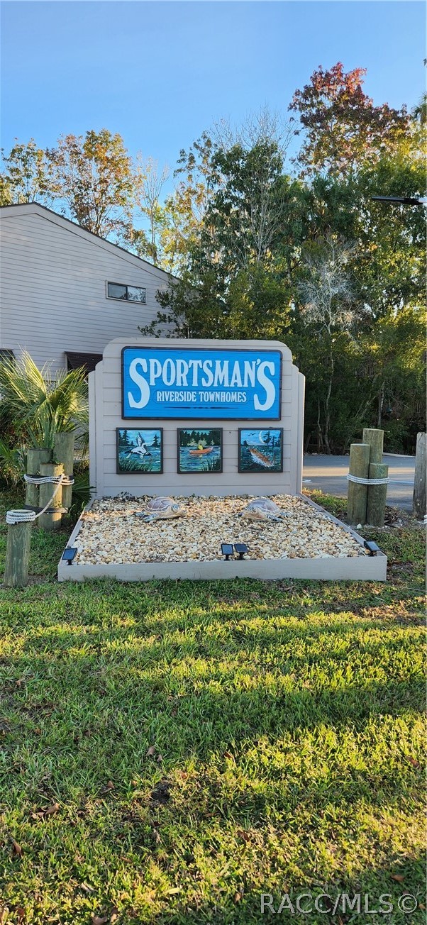 Sportsman's Riverside Townhomes entrance sign in a landscaped stone bed beside a grassy lawn.