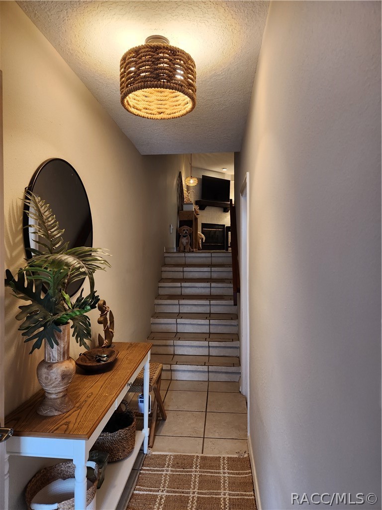 Entry hallway with tiled stairs, a wooden console table, and a woven pendant light.