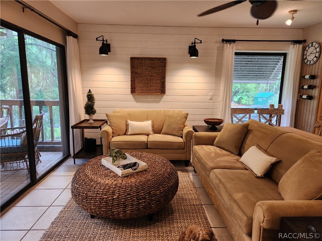 Furnished living room with tan sofas, a woven round coffee table, and sliding doors to a deck.