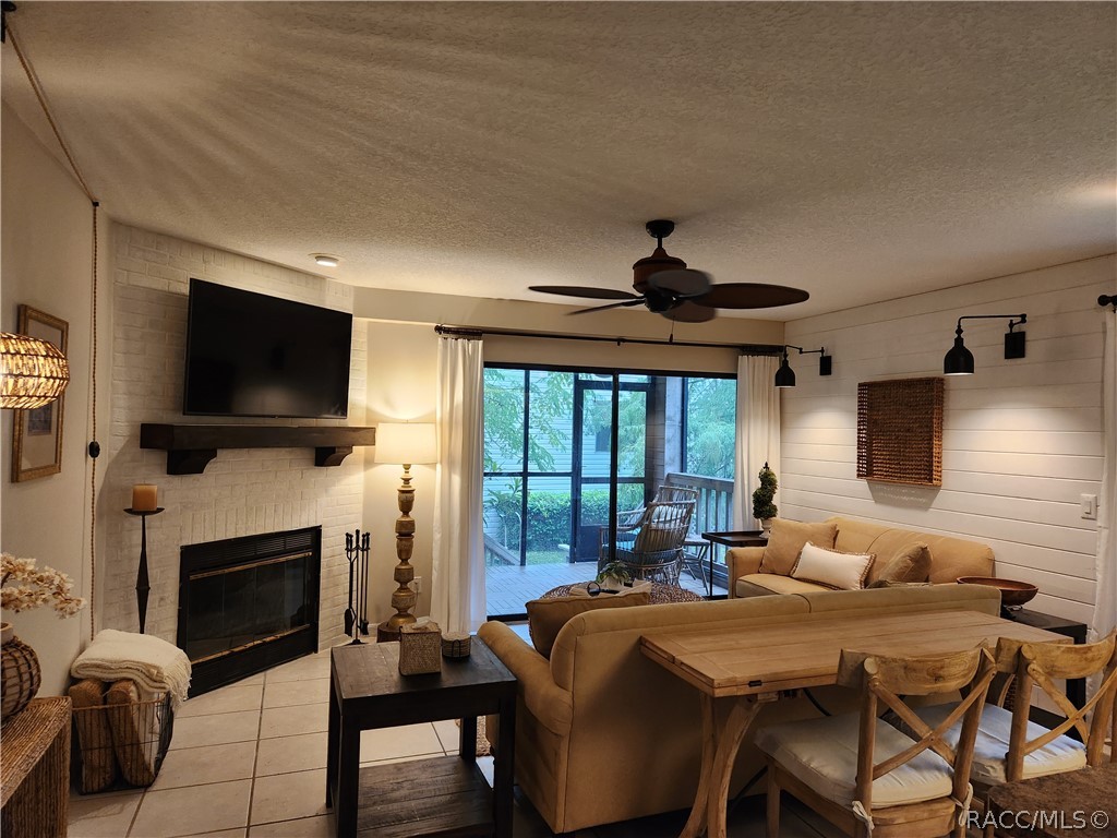 Furnished living room with a white brick fireplace, tan sofas, and sliding doors to a screened porch.