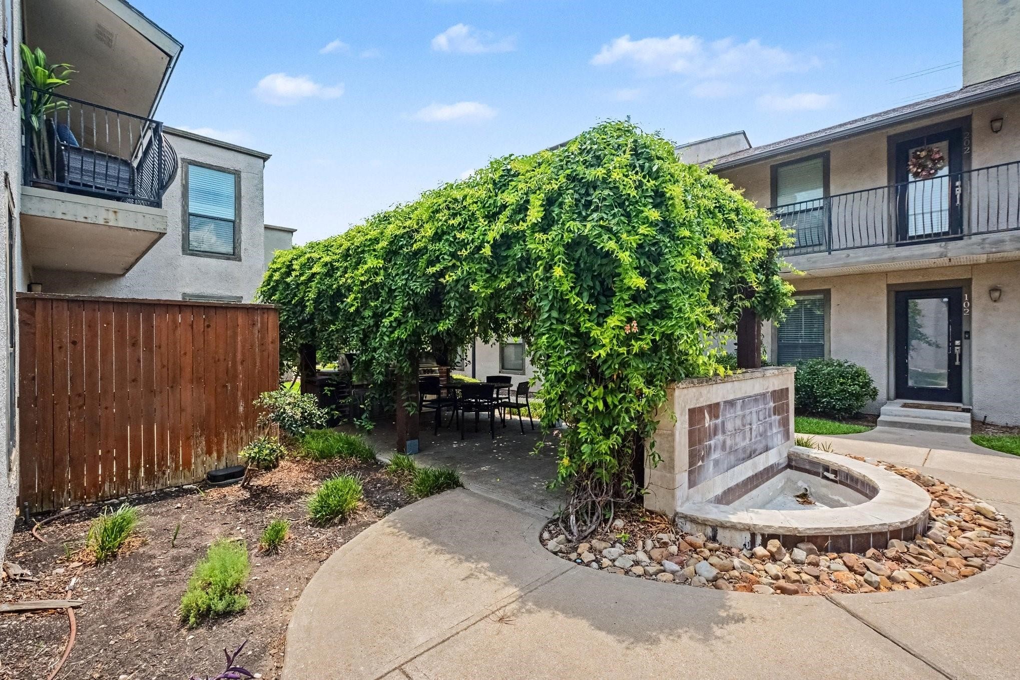 Condominium courtyard with a vine-covered dining area and curved fountain basin.