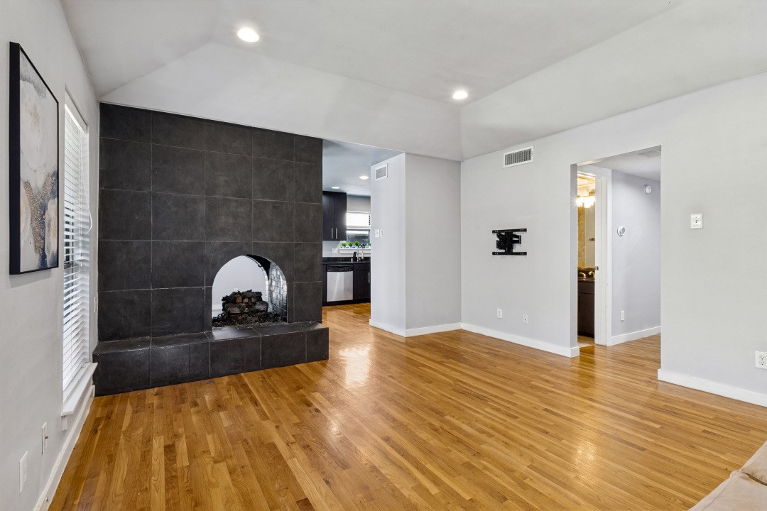 Living room with hardwood floors and a large dark tiled fireplace.