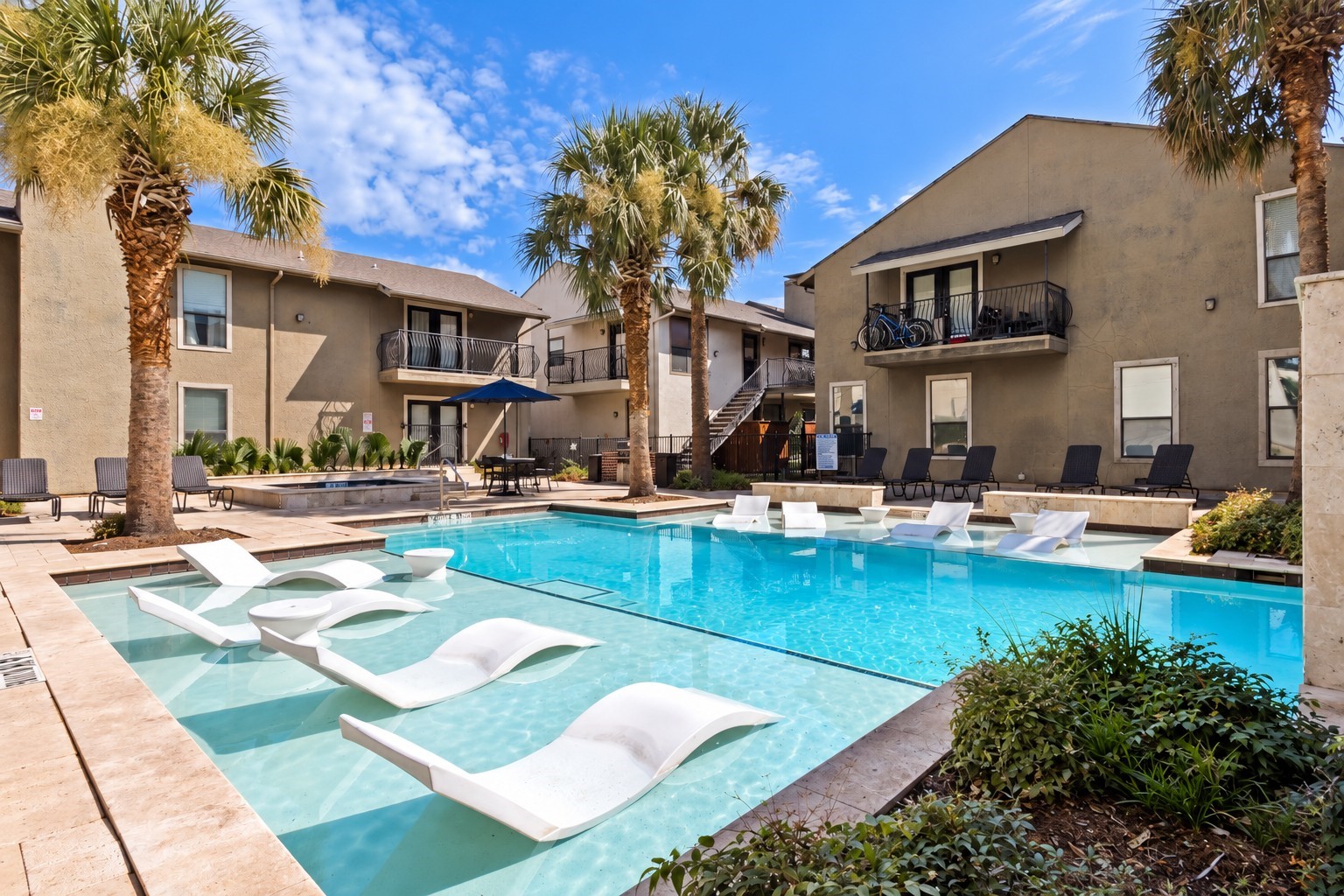 Apartment courtyard pool with palm trees and white in-water loungers