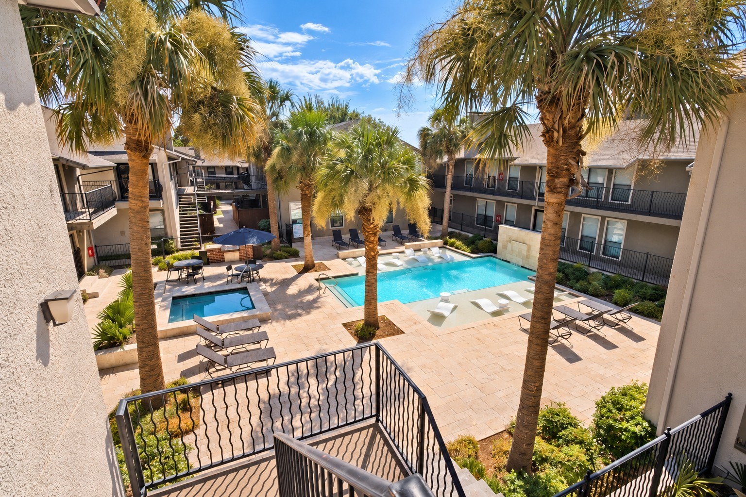Apartment courtyard with two pools, palm trees, and surrounding two-story buildings.