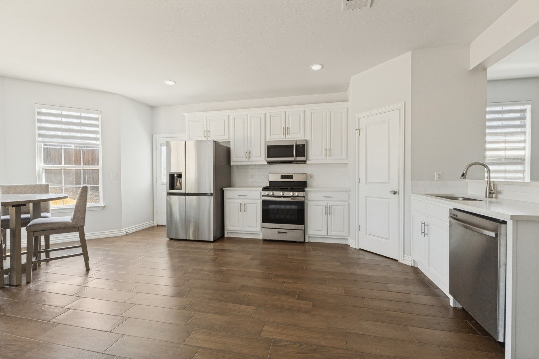 Kitchen with white cabinets, stainless steel appliances, and brown tile flooring.