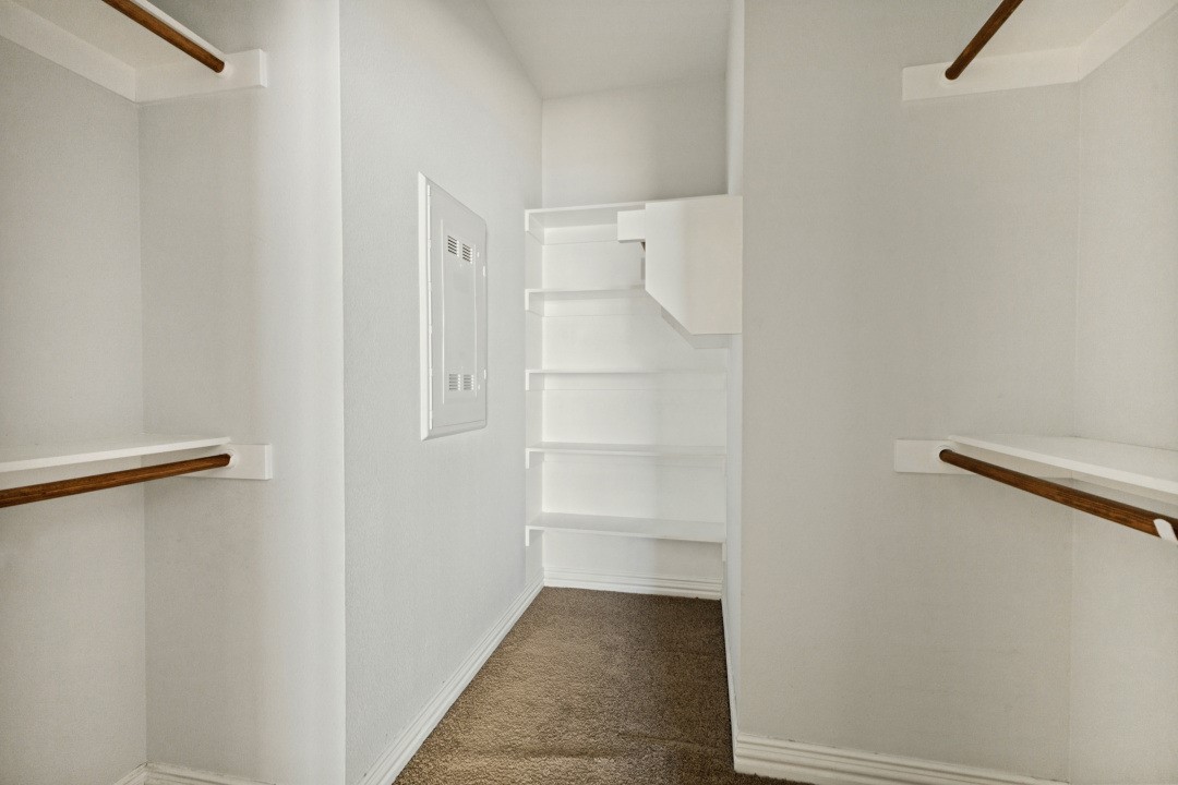 Walk-in closet with wooden hanging rods and built-in shelves.