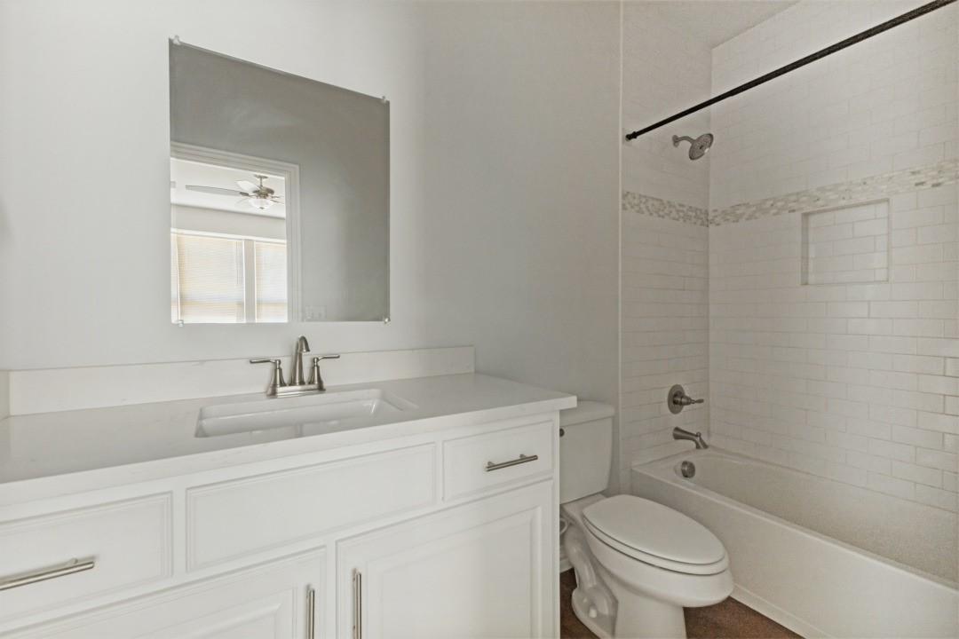 Bathroom with a white paneled vanity, large mirror, and subway-tile tub and shower.
