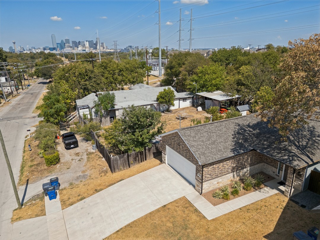Aerial view of a single-story home and fenced yard, with downtown Dallas in the distance.