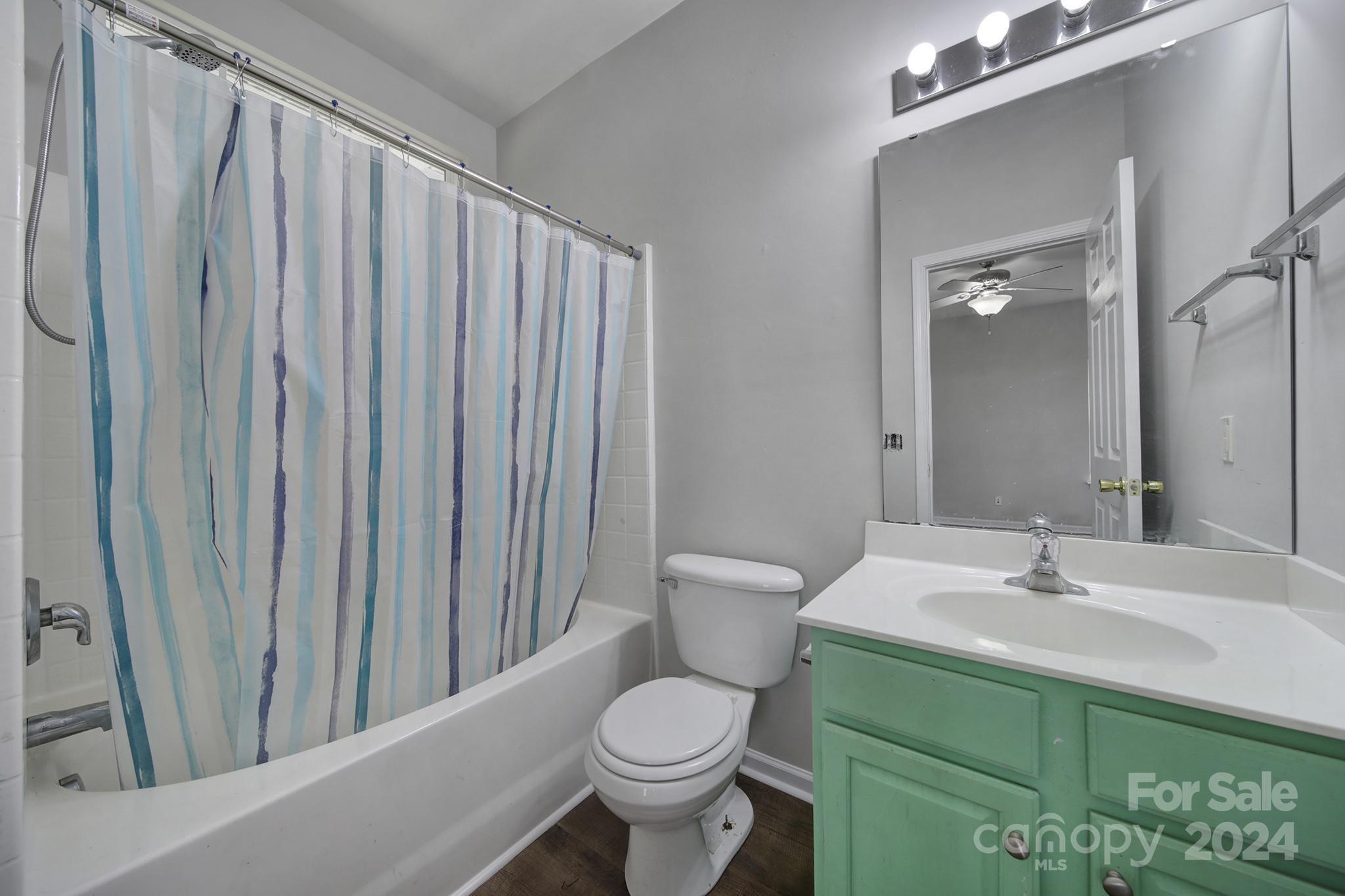 Bathroom with a blue-striped shower curtain and green vanity.