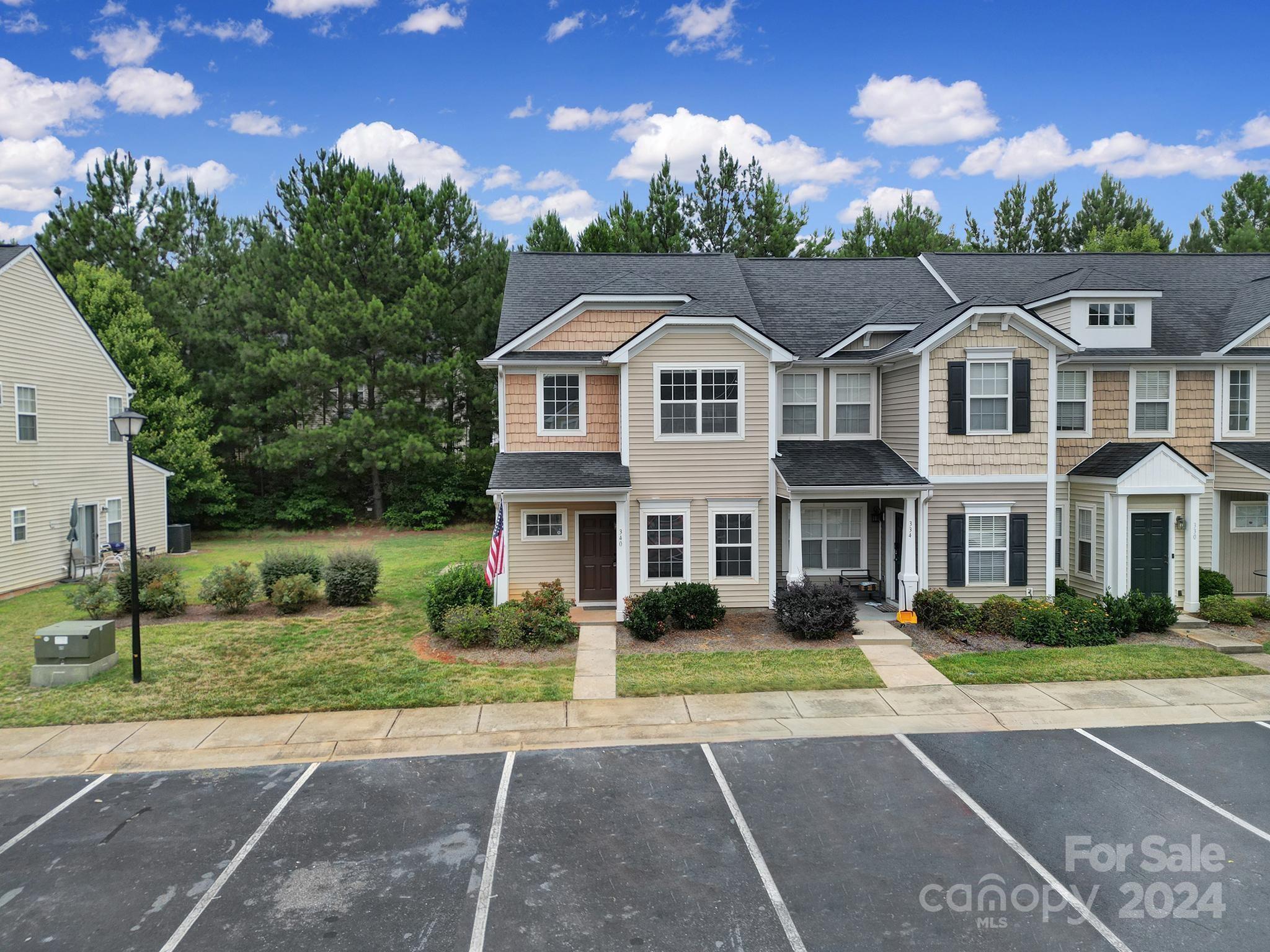 Two-story townhouse with tan shingle accents, an American flag, and parking spaces in front.