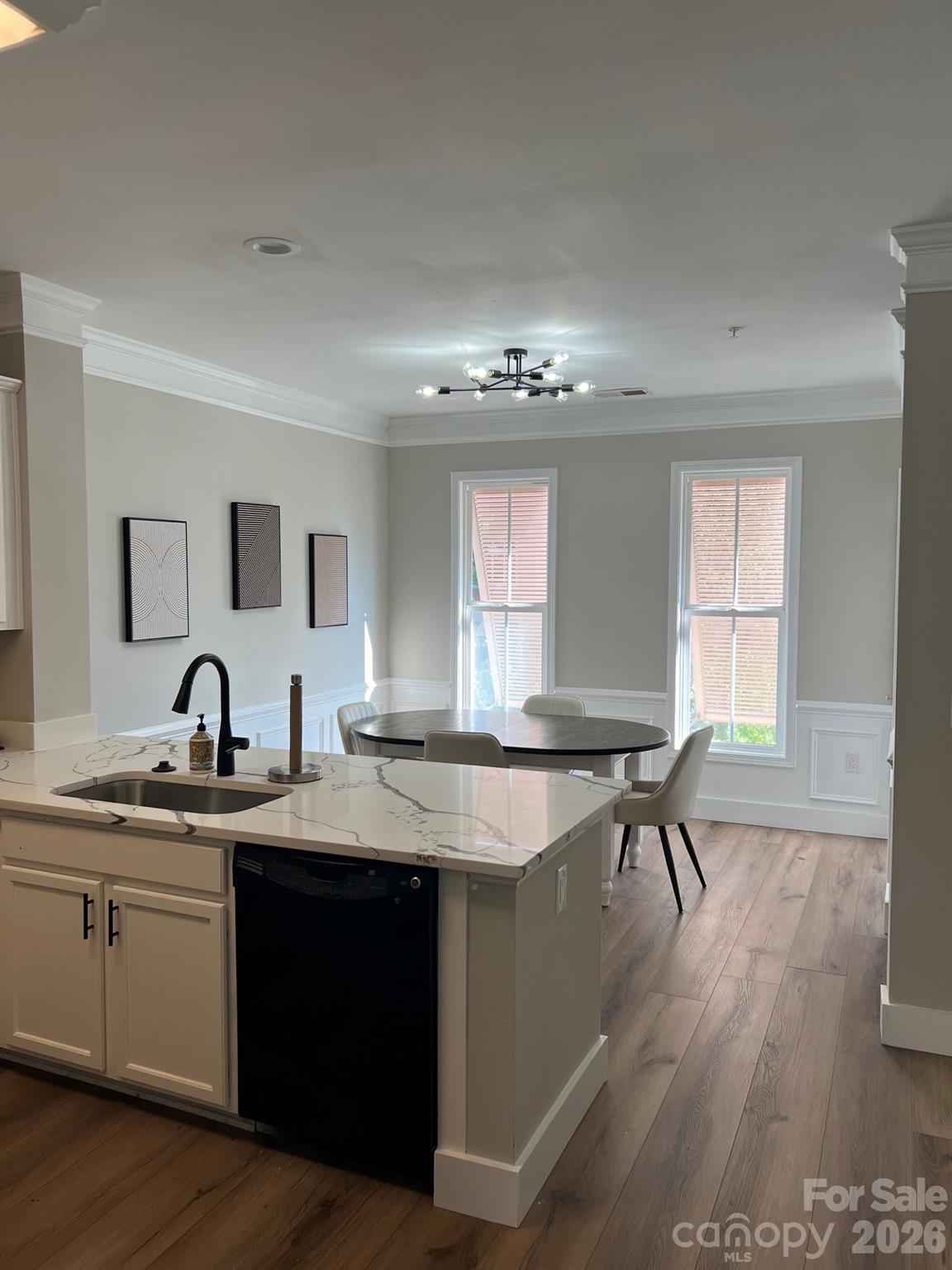 Kitchen island with veined stone counters opens to a dining area with a round table and tall windows.