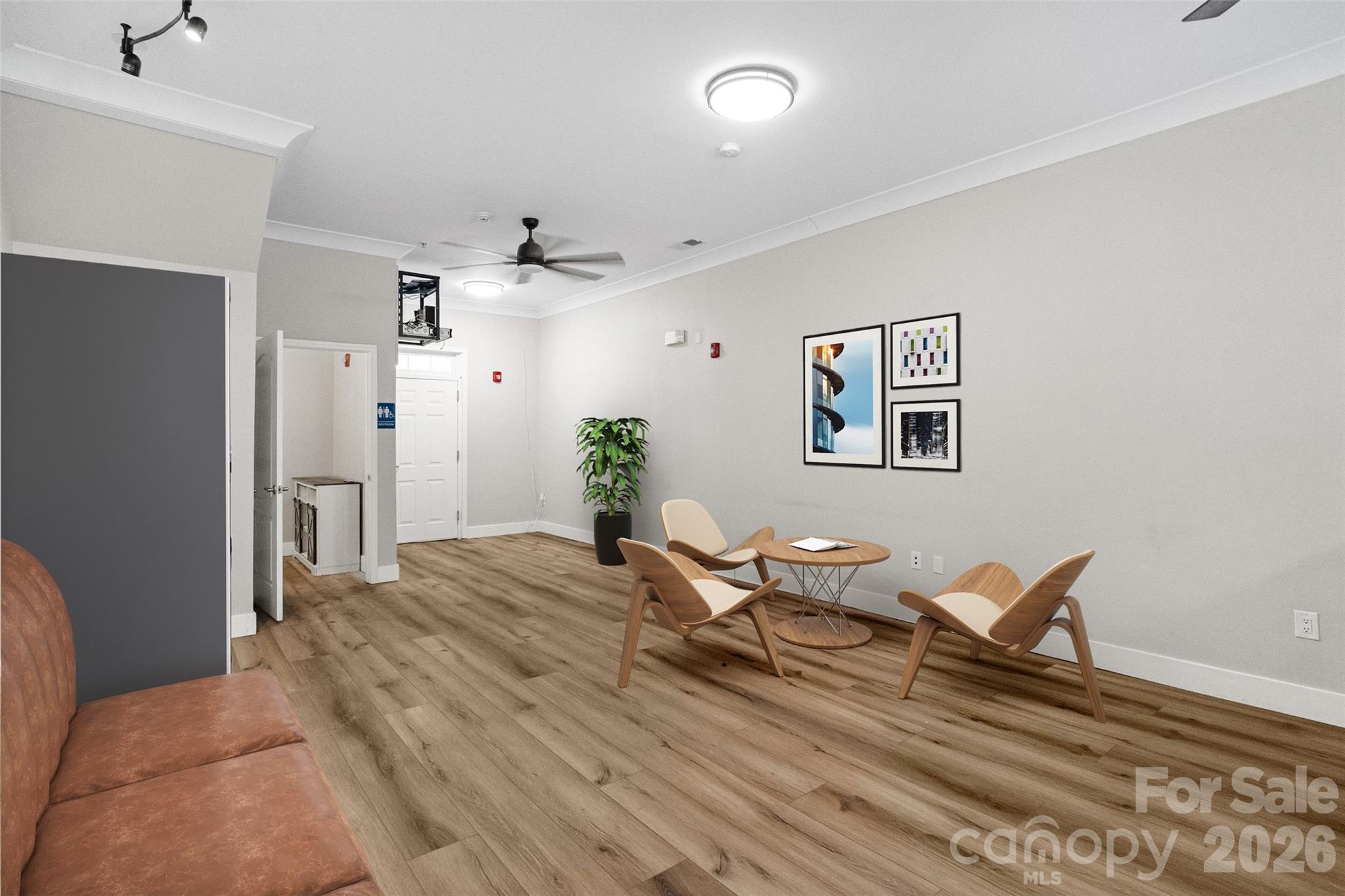 Furnished sitting area with modern lounge chairs, a round table, and wood-look flooring.