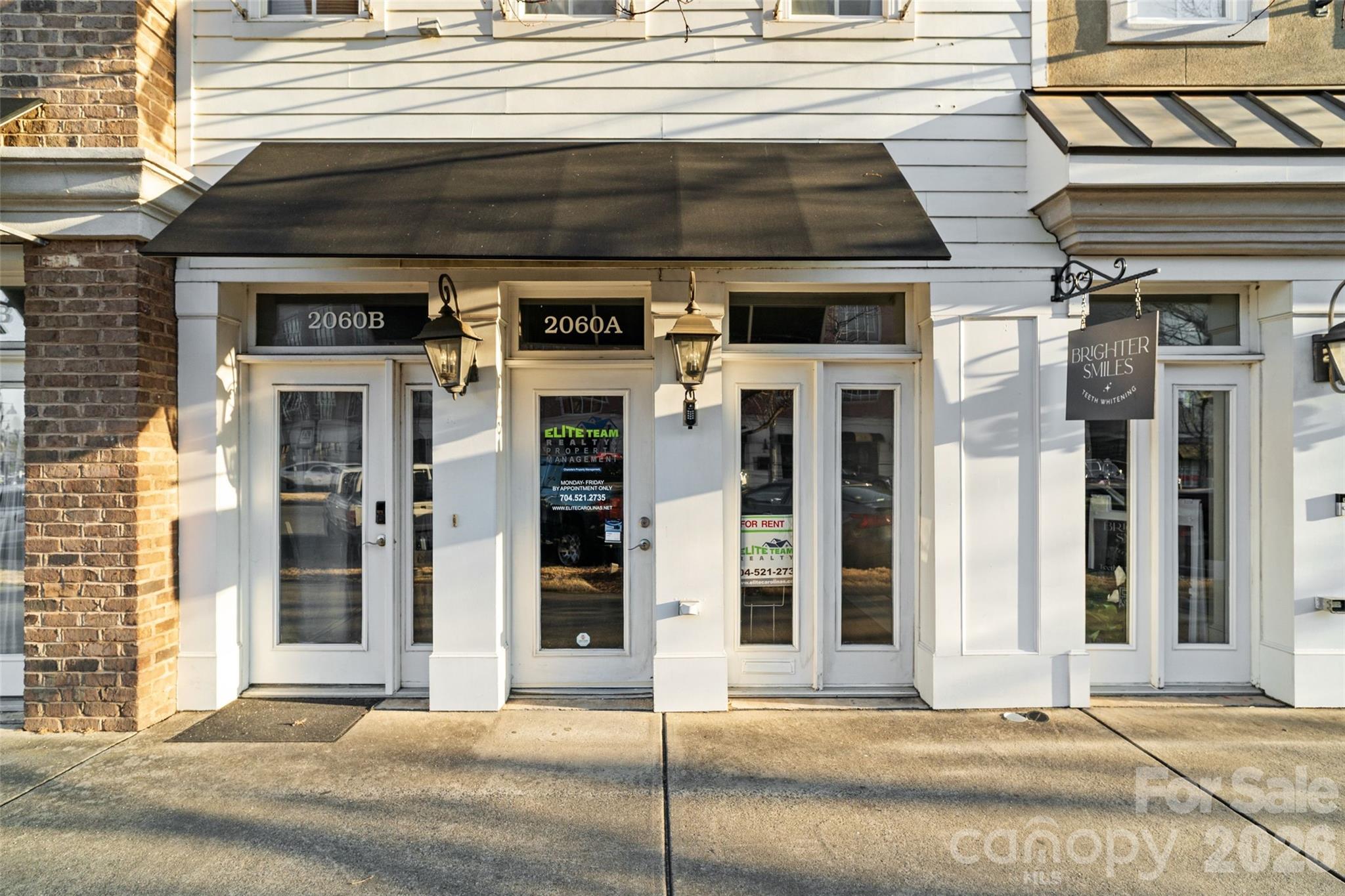 Commercial storefront with white siding, black awning, and entrances marked 2060B and 2060A.