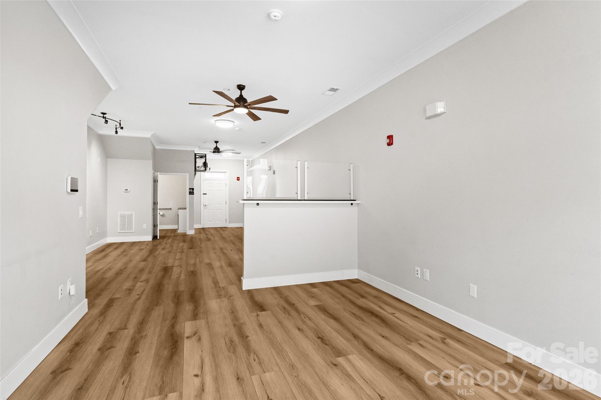 Vacant commercial interior with wood-look floors and a glass-panel reception counter.