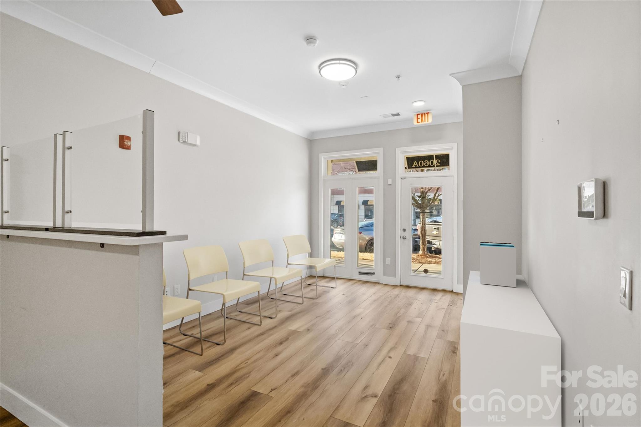 Office reception area with pale waiting chairs, a counter, and glass entry doors.