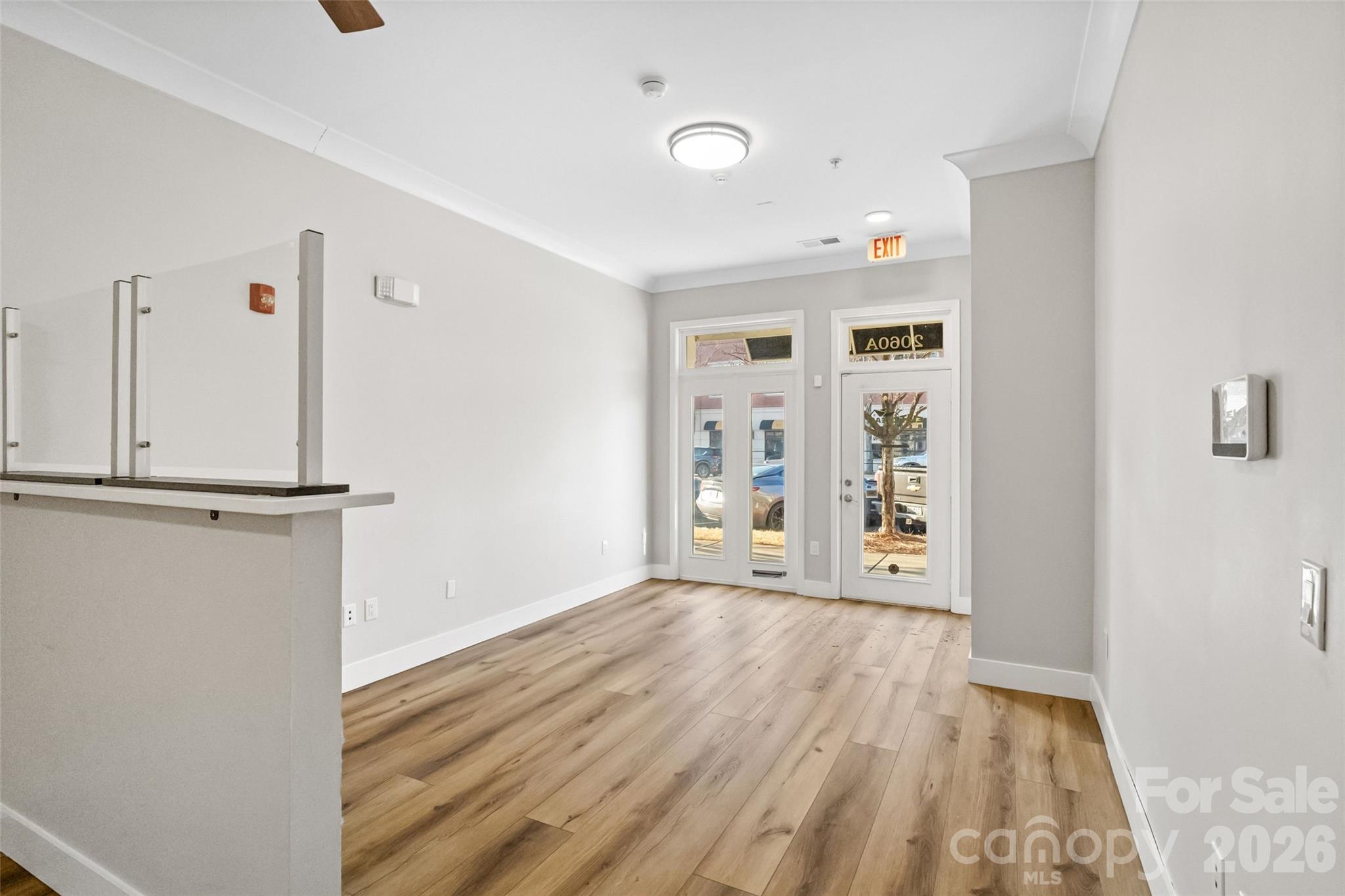 Vacant commercial lobby with a reception counter, wood-look flooring, and glass entry doors.