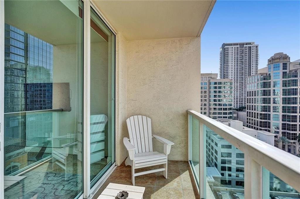 Condo balcony with a white Adirondack chair and views of downtown high-rises.