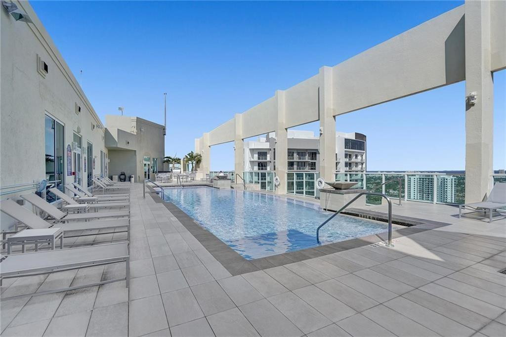Rooftop pool with tiled deck, lounge chairs, and distant Fort Lauderdale high-rises.