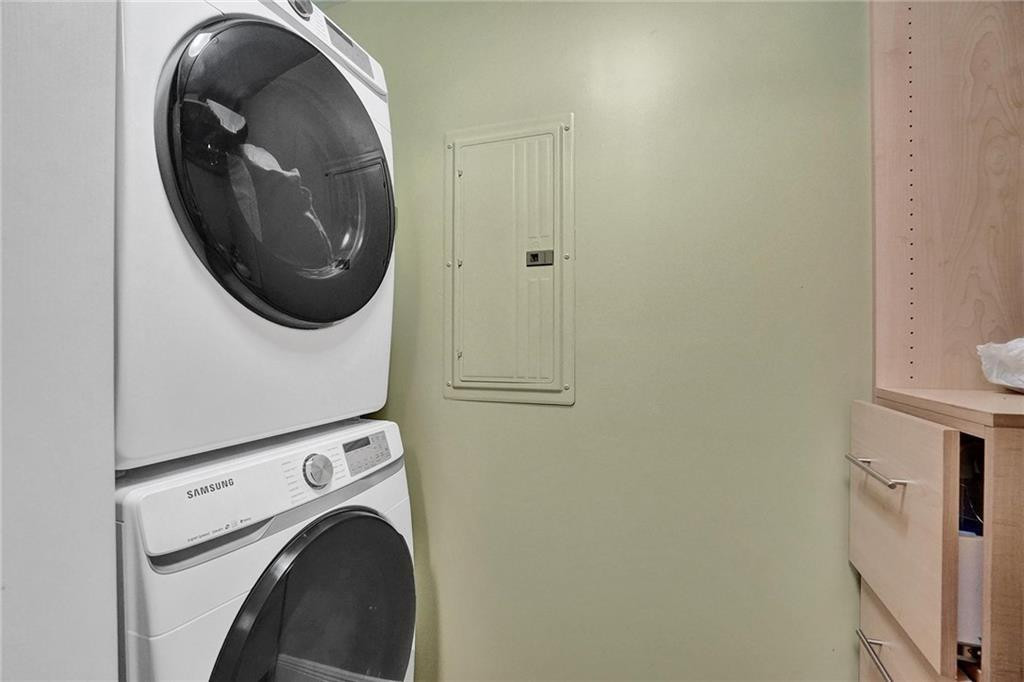 Laundry area with stacked Samsung washer and dryer beside light wood cabinetry.