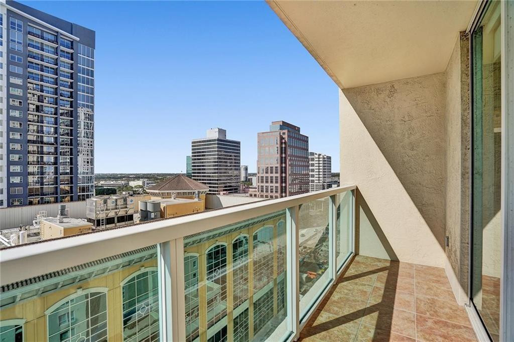 Condominium balcony overlooking downtown Fort Lauderdale, with terracotta tile flooring and a glass railing.