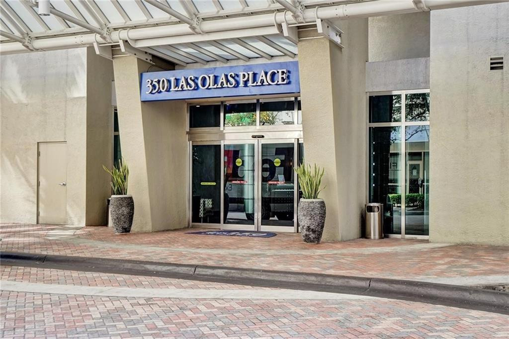 Entrance to 350 Las Olas Place beneath a white canopy, flanked by potted plants.