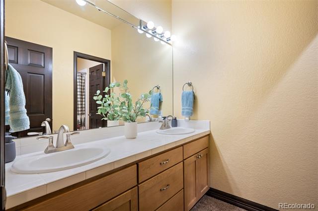 Bathroom with a double-sink wood vanity, large mirror, and blue towels.