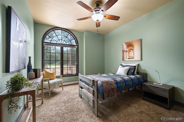 Bedroom with blue patterned bedding, a large arched window, and a small seating area.