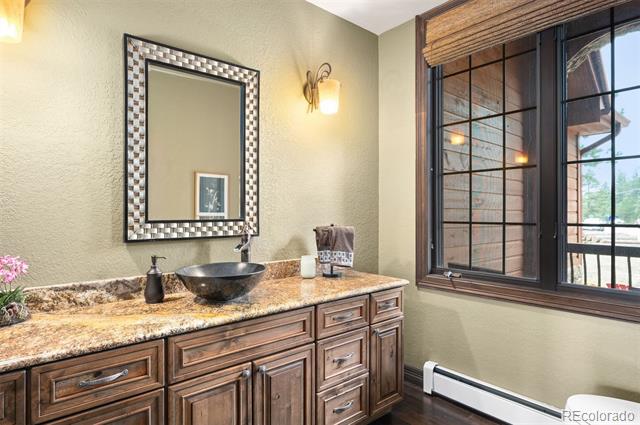 Bathroom with a wood vanity, dark vessel sink, checkerboard-framed mirror, and large window.