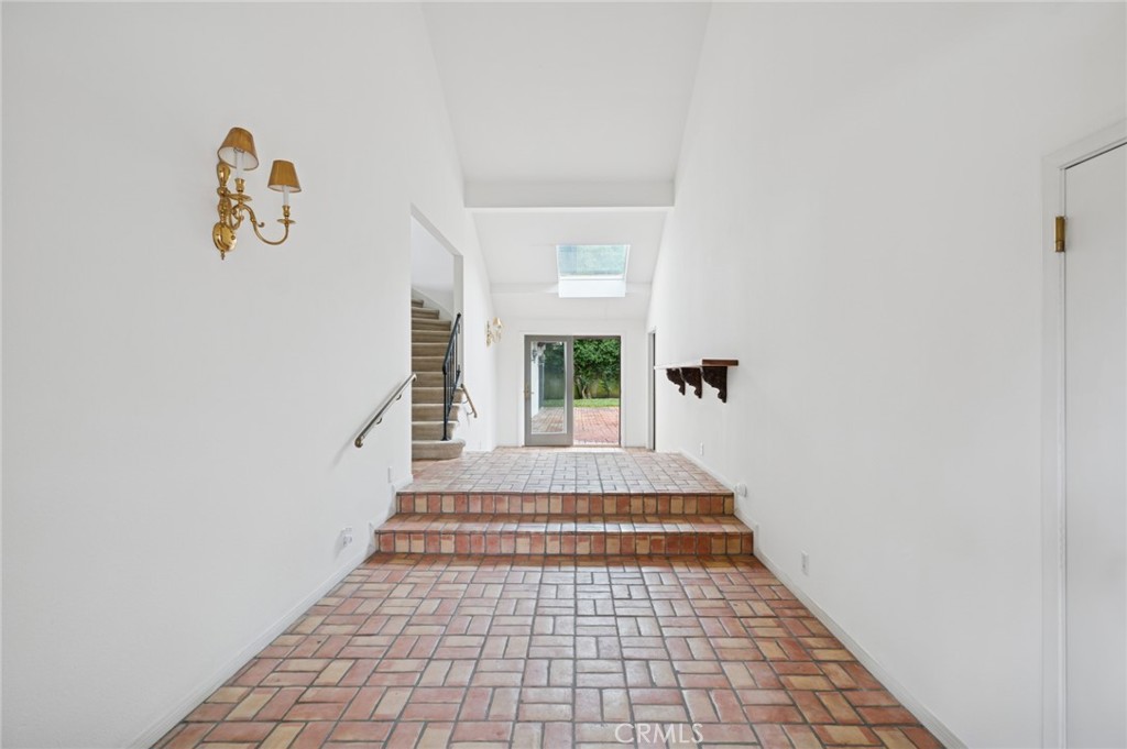 Entry hall with brick-pattern tile flooring, a skylight, and glass doors opening to a patio.
