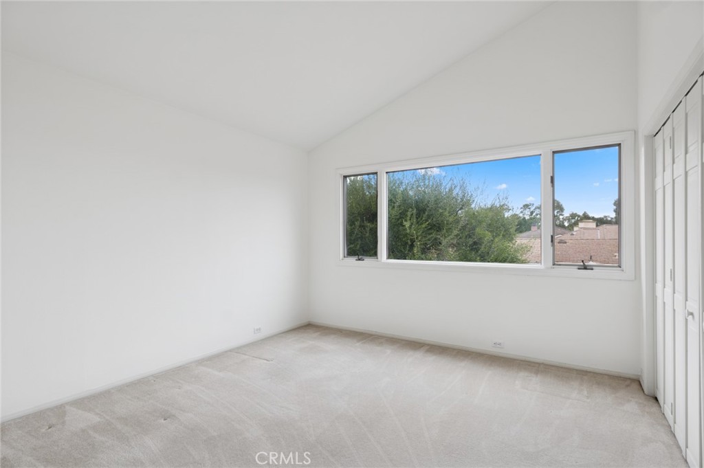 Vacant bedroom with a wide window overlooking trees and a built-in closet.