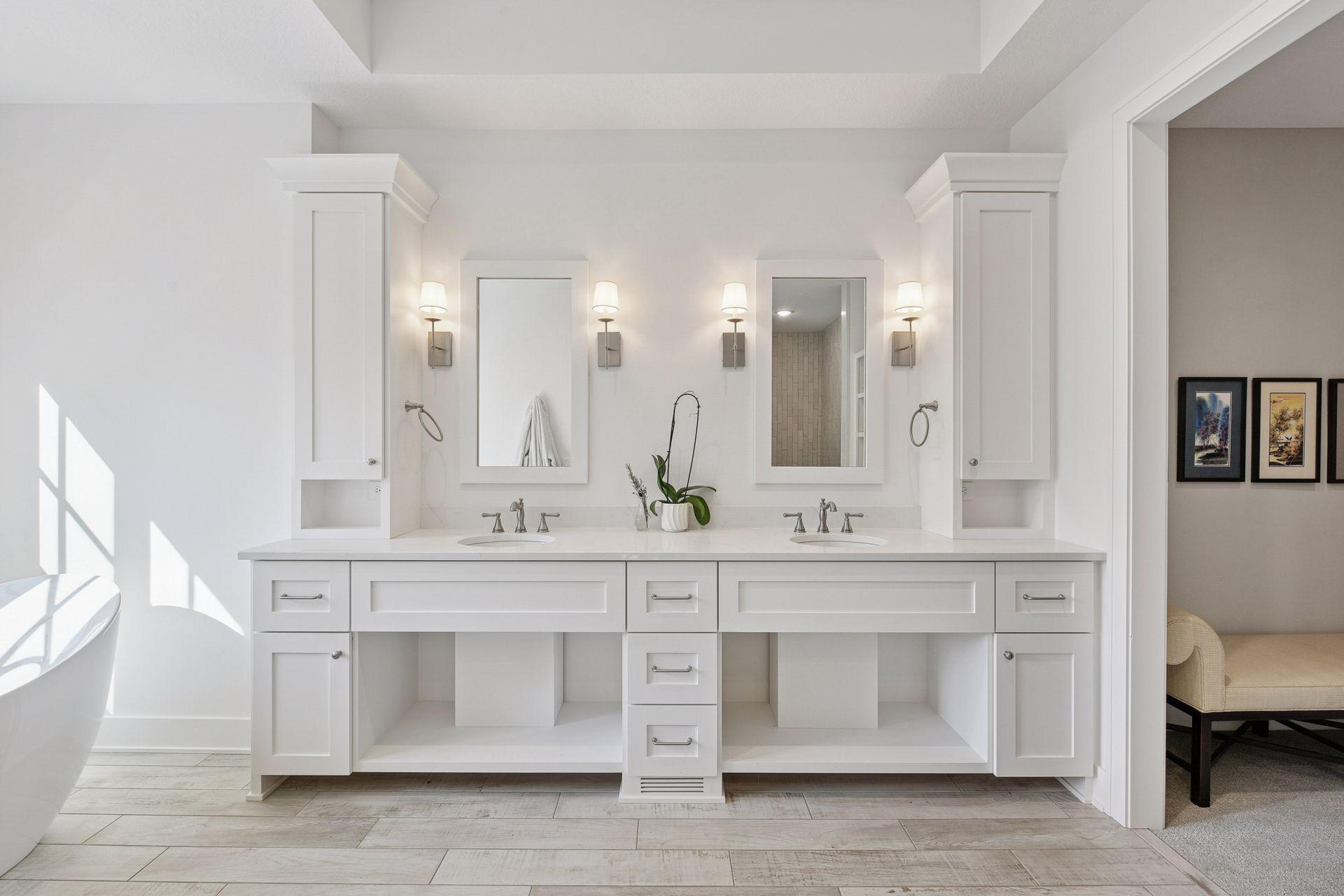 Bright bathroom with a white double vanity, twin mirrors, and a freestanding tub.