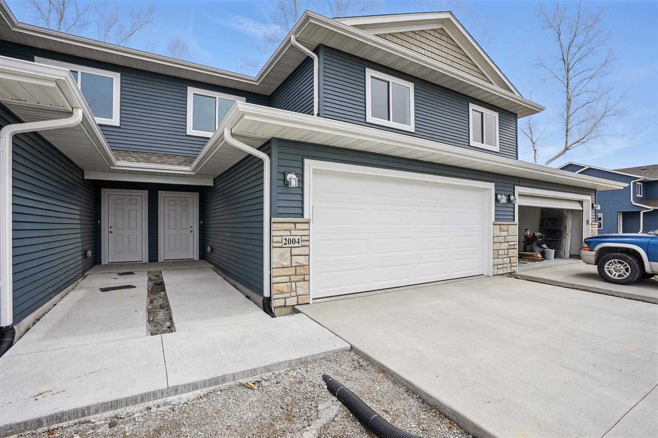Blue-gray two-story home with stone accents, two entry doors, and attached garages.