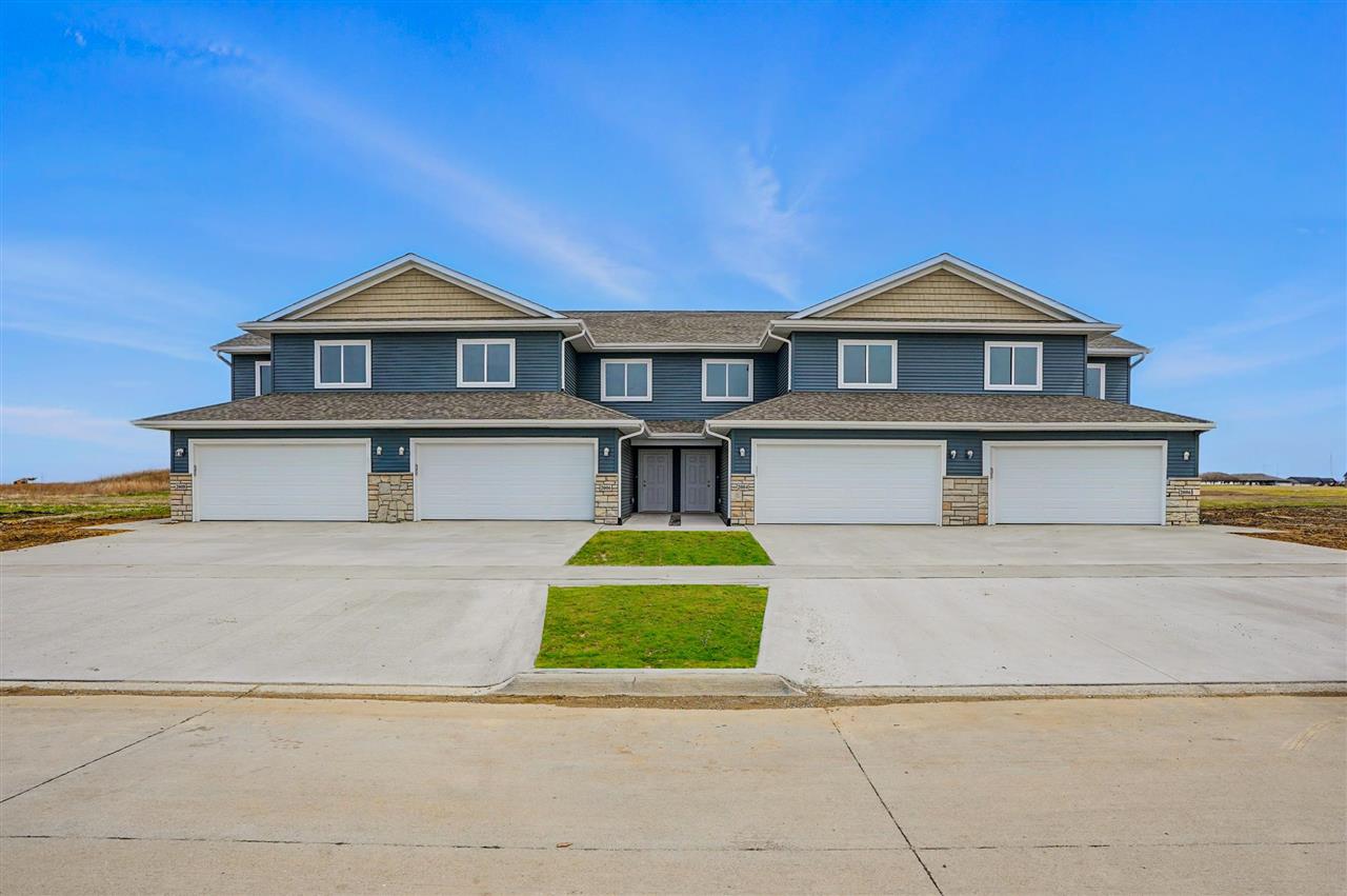Two-story blue-sided attached homes with stone accents and four white garage doors.